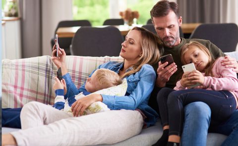 Rodzina na kanapie. Wszyscy zapatrzeni w swoje telefony komórkowe.